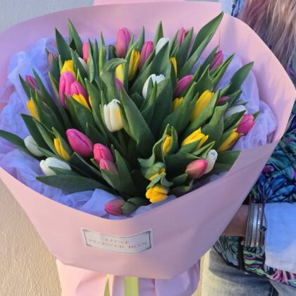 Tulip bouquet featuring charming white, pink, and yellow tulips in a pink wrapping, perfect for expressing love.