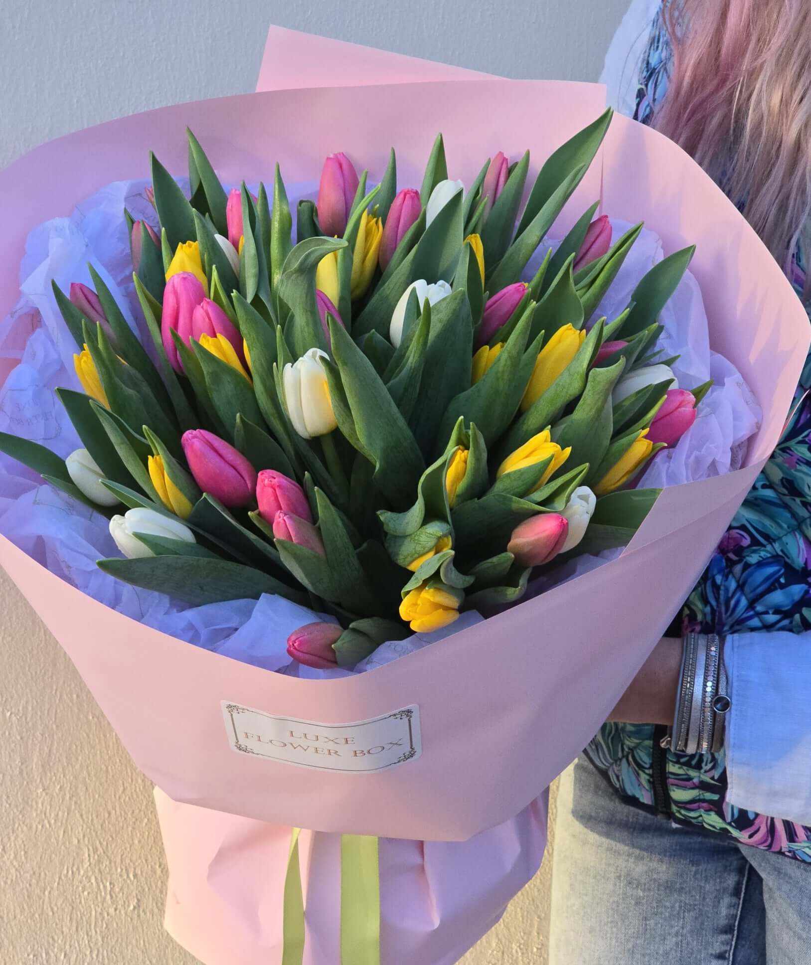 Tulip bouquet featuring charming white, pink, and yellow tulips in a pink wrapping, perfect for expressing love.
