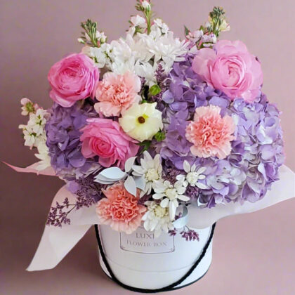 A luxurious flower box featuring a harmonious arrangement of ranunculus, carnations, and hydrangeas in soft, elegant tones, perfect for adding a touch of grace and beauty to any special occasion.