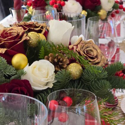 Decorative floral arrangement with red, gold, and green elements on a table.
