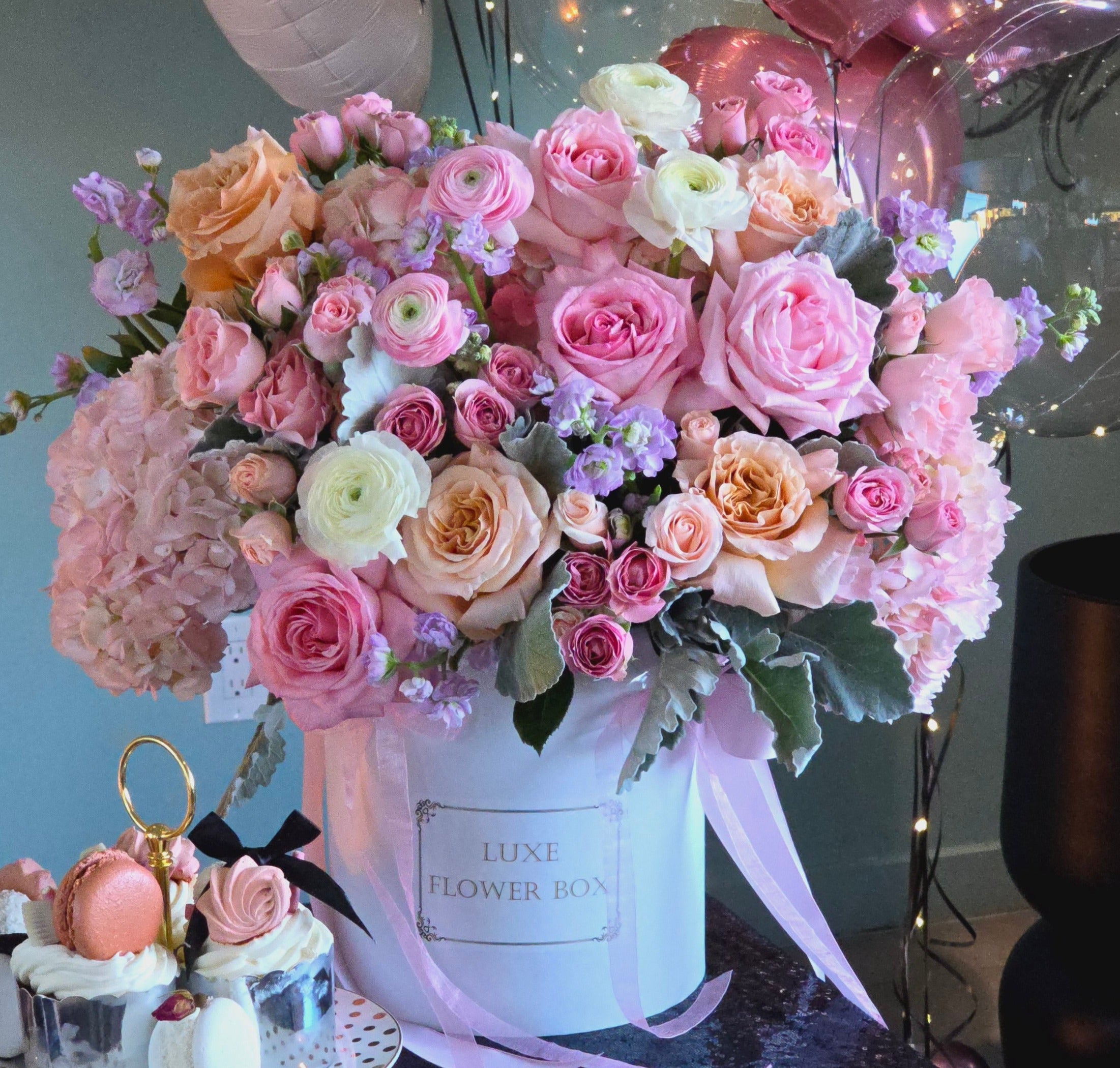 Coquette flower box arrangement featuring garden roses, ranunculus, and pastel blooms in a luxe container.